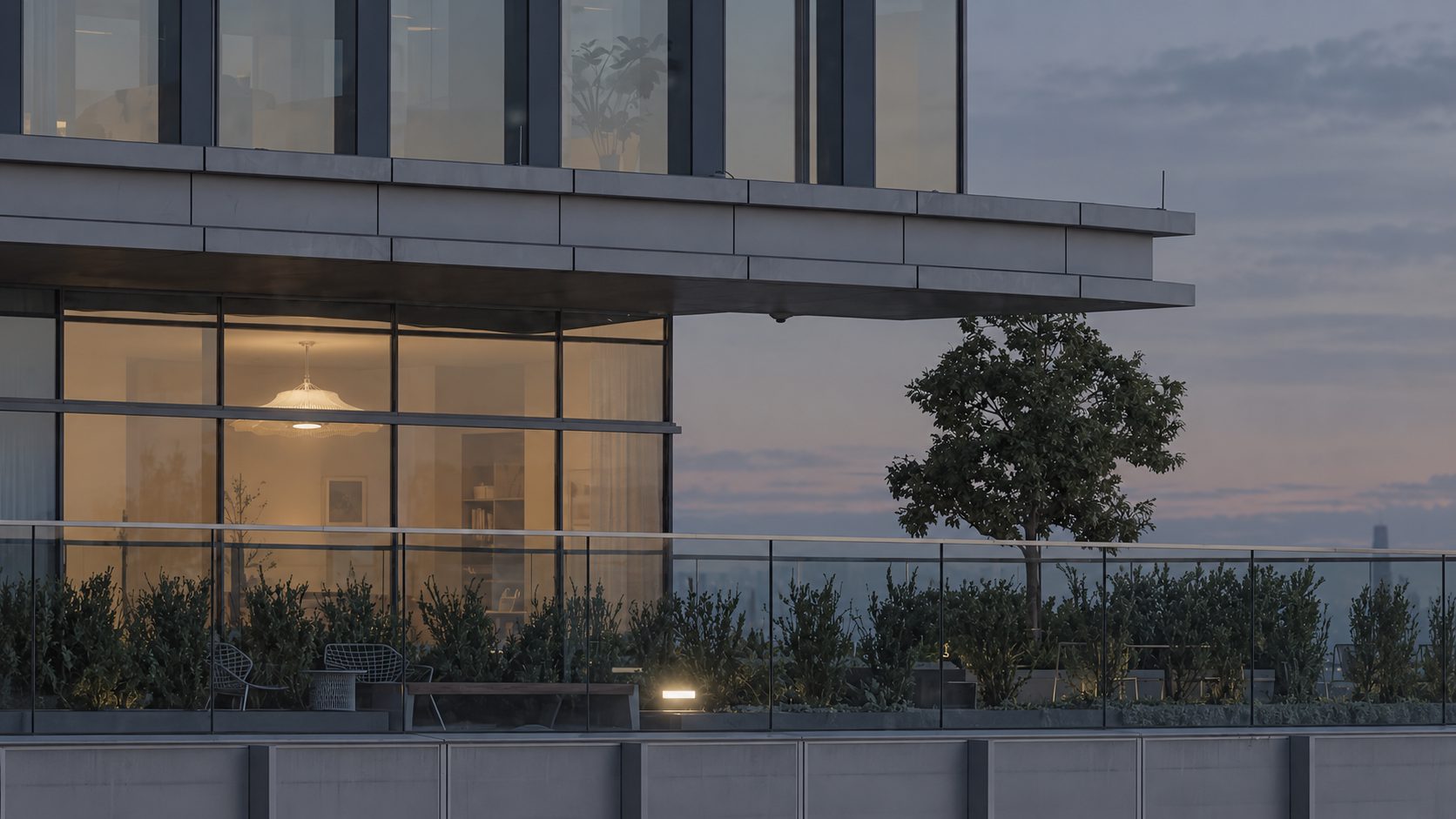 Lumen glowing in a glazed apartment at dusk, seen from a rooftop terrace